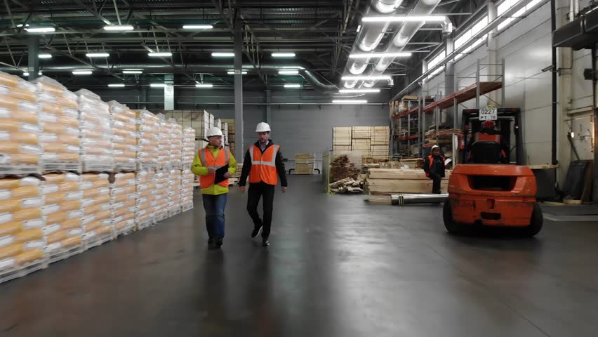 Two workers of warehouse team discussing while walking in warehouse. Aerial, top view. Royalty-Free Stock Footage #1020927886