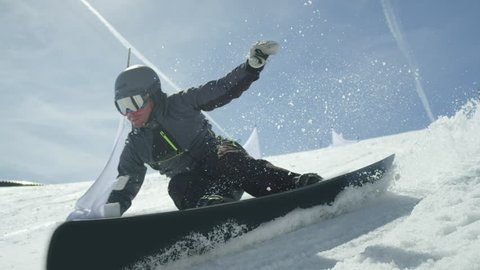 SLOW MOTION CLOSE UP: Racing snowboarder riding slalom between gates