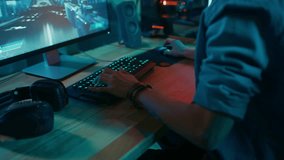 Close Up Hands Shot Showing a Gamer Pushing the Keyboard Buttons while Playing an Online Shooter Video Game. Keyboard Led Lights Change Color in Rainbow Spectrum. Gamer is Wearing a Bracelet.