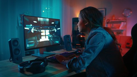 Beautiful and Excited Black Gamer Girl is Playing First-Person Shooter Online Video Game on Her Computer. Room and PC have Colorful Neon Led Lights. Cozy Evening at Home.
