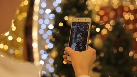 Woman Hands Shooting Video Of Christmas Lights And Decorations By Smartphone At The Holiday Party. Closeup.