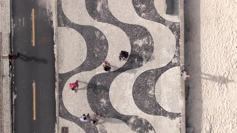 Rio de Janeiro, Brazil, flying directly above the iconic Copacabana Beach mosaic sidewalk.