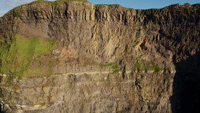 Aerial drone footage of the beautiful Cliffs of Moher off the west coast of Ireland along the Wild Atlantic Way. Scenic view of mountain cliff against sky. Drone flying upwards revealing cliff face