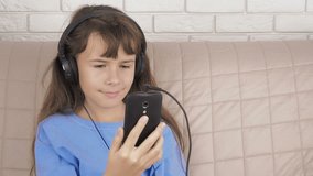 Child with a smartphone. The girl rubs tired eyes from the smartphone.