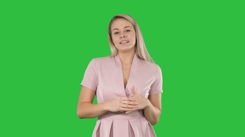 Excited beautiful young woman in pink dress talking to camera on a Green Screen, Chroma Key.