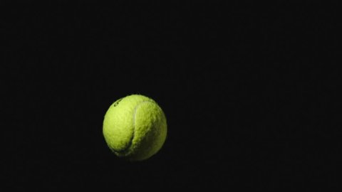 SLOW MOTION: Tennis ball flies up and falls down on a black background