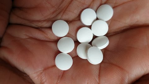 White drug pill tablets on human hand palm