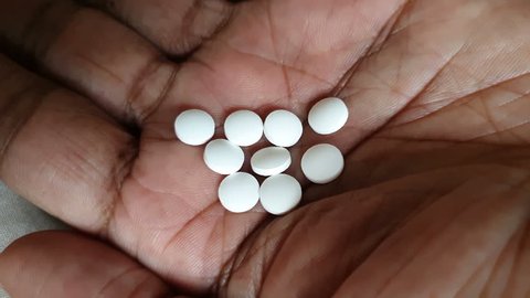 white drug tablet fall on asian palm with more tablet pills