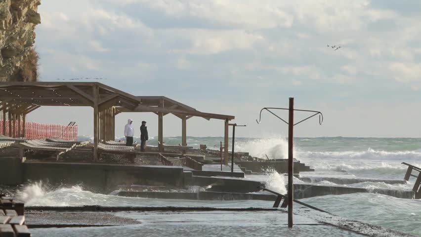 People seeing at the sea storm. Huge powerful waves breaking at seawall in major severe storm. Russia, Anapa city
