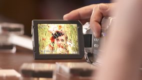 Man watching family home video on LCD screen of digital Mini DV camcorder. Young woman in summer on display of obsolete miniDV video camera.