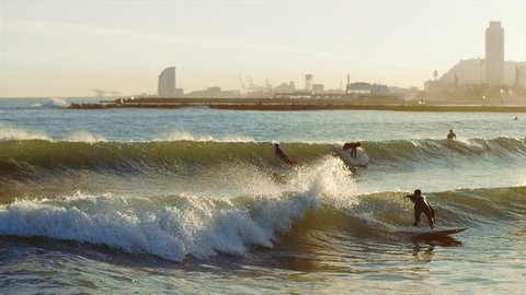 Surf practice. Barcelona Sea Coast at Sunset. Defocused Surfers and City Skyline view with Amazing Sun Light over the Mediterranean Sea. Original, not common, unusual view of fantastic Barcelona City 