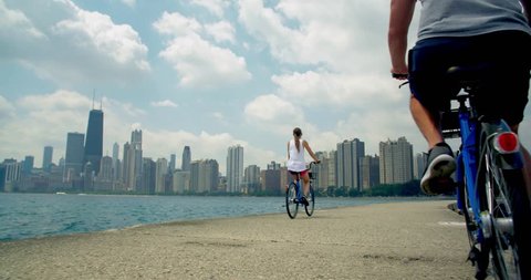 Couple Bikes Across Beach, Chicago Skyline Behind