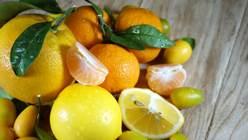 Fresh citrus fruits. Lemon, mandarin, orange and kumquat rotating on a wooden table. Footage of the concept of a healthy food and diet. 4K Royalty-Free Stock Footage #1020986470