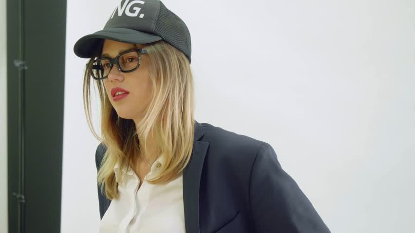 Model in black baseball cap and balck jacket poses during photoshoot