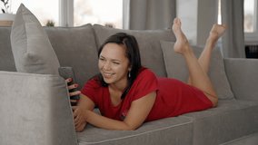 Lifestyle shot of family time, girl running up to mother in living-room. American woman using smartphone, talking with daughter in room. Two person having fun together, smiling, communication. Concept