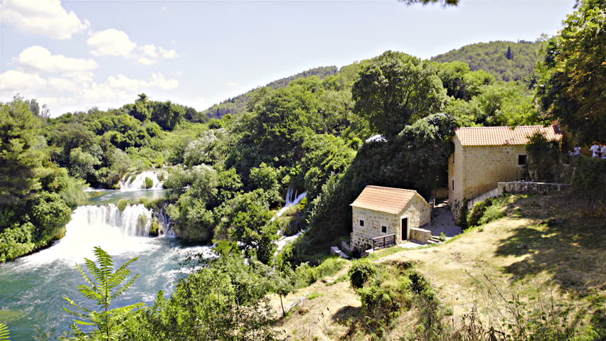 Old traditional house next to paradise waterfalls wide shot HD. Slight panning wide view of lonesome traditional architecture next to river with waterfall in middle of nature. Surrounded with forest.