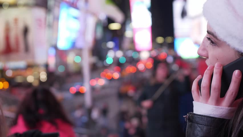 Young woman takes a phone call on Times Square by night