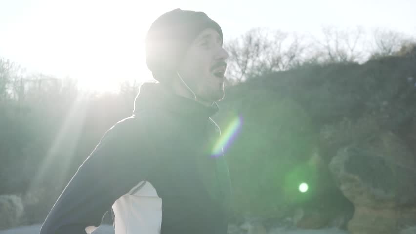 Young male runner training outdoors in the cold weather, athlete workout on the autumn beach