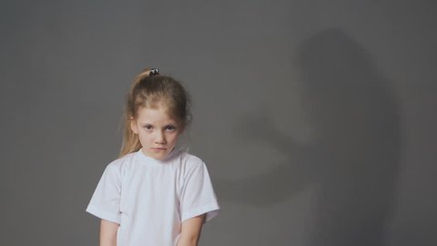 Shadow of angry mother scolds upset daughter. Domestic violence and children abuse concept.