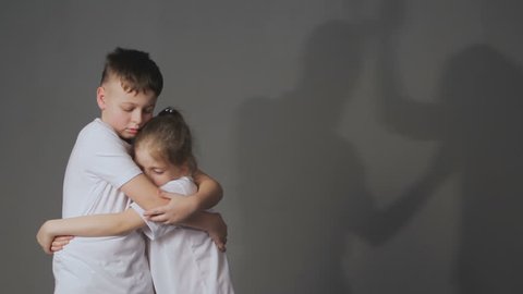 Little boy and girl and silhouettes of quarreling parents on background. Shadows of parents fighting, upset daughter and son in foreground. Domestic violence concept.