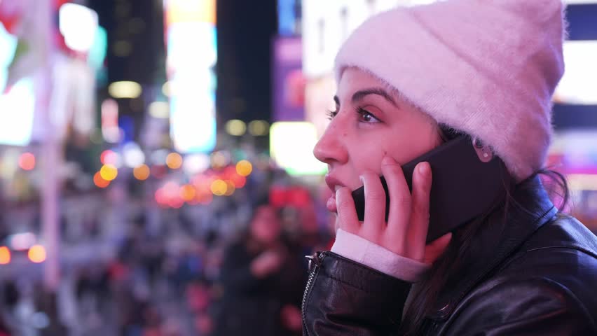 Young woman takes a phone call on Times Square by night