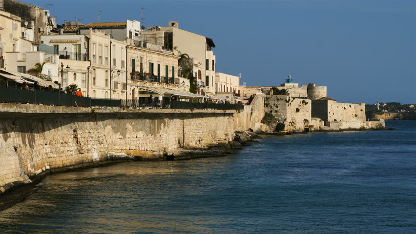 Syracuse,Ortygia, Sicily, Italy. People walking on the Lungomare Alfeo. In the background is  the Castello Manace