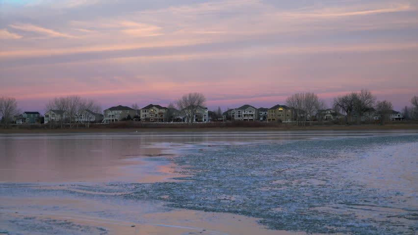 Lake freezing after winter sunset with a residential houses - Boyd Lake State Park in Colorado