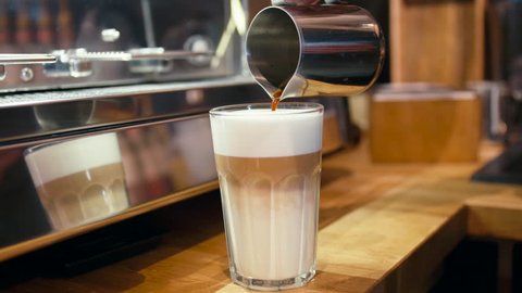 Barista is Pouring Coffee to a Glass with Milk Froth to Make a Latte Macchiato or Flat White in the Cafe Shop