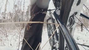 Action cam on frame installed behind. Close-up pov view. Professional extreme sportsman biker riding fat bike in outdoors in winter snow forest.