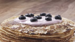 Slow motion of grating fine chocolate on blinis with yogurt and blueberries