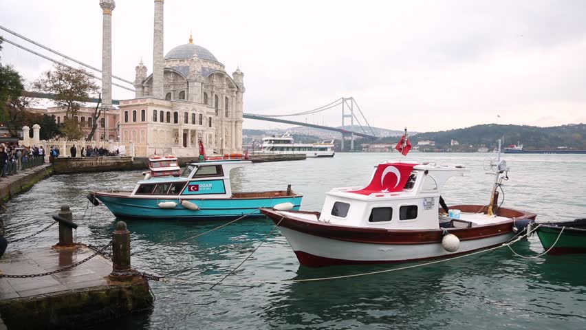 Ortakoy mosque and Bosphorus bridge in Istanbul at dusk, Turkey. Long exposure shot with blurred fishing boats on the little harbor. Vintage filter applied to warm up the mood of the photo.