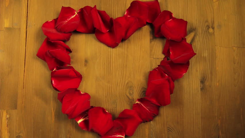 The girl puts in the middle of the heart of rose petals a cup of coffee.