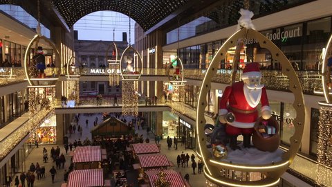 Berlin, Germany - December 16, 2018: Shopping "Mall of Berlin" decorated for Christmas with a big wooden Santa Clause, busy with many Shoppers and illuminated with thousands of lights. Christmas Marke