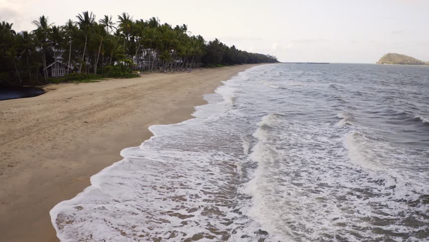 Aerial, beautiful view on a beach of Palm Cove, right above the ocean waves in Cairns, Queensland, Australia