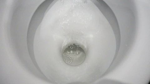 Toilet Flushed Top Down View. Close-up view of a Water flushing down into the toilet bowl in bathroom. Slow motion shot of water being flushed in a toilet bowl. 