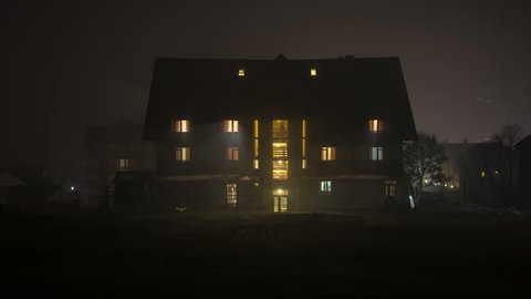 A night time exterior home as a room lights up then turns off. Time lapse shot of house at night. 8K. 4K.