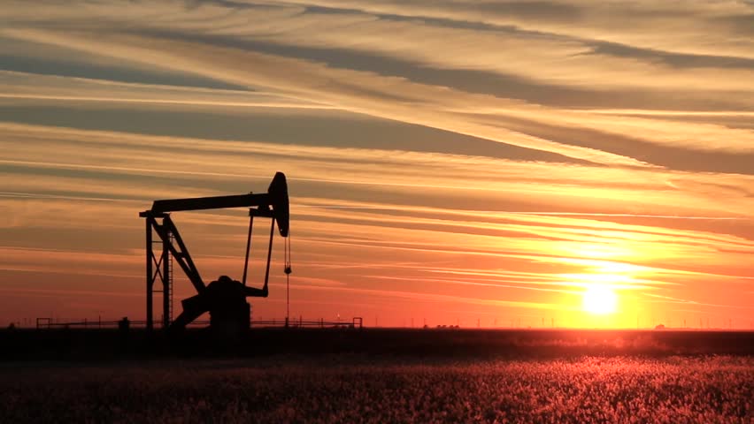 Silhouetted pump jack in the oil field at sunset