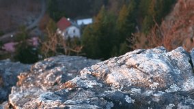 Rocks with view of deep valley and house. 4K resolution trucking shot. Shallow depth of field.