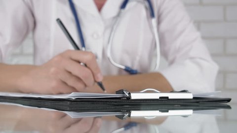 Doctor writing on medical card. Doctor fills out a medical card.