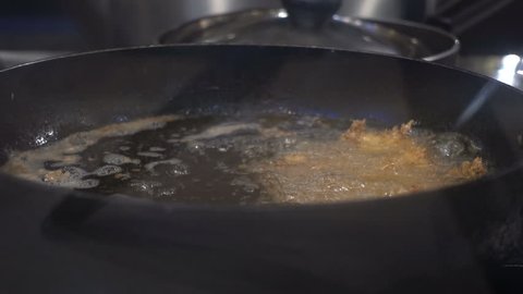 Frying pork in a pan with boiling oil