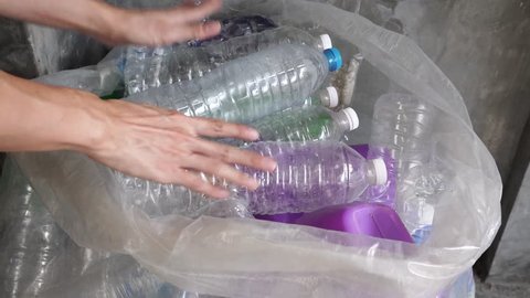 Hand getting plastic bottles to dispose in garbage bag ready to recycle, waste management and plastic recycle