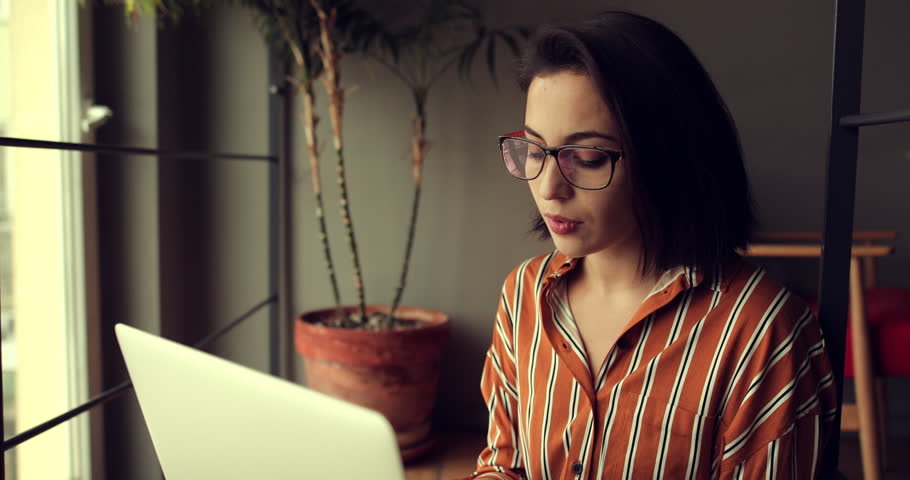Businesswoman wear glasses in office, work on laptop and think about new ideas with pen. Girl using laptop for work, copy space Royalty-Free Stock Footage #1021092571
