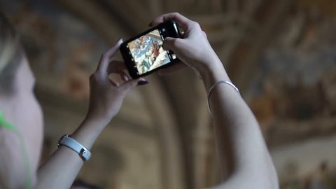 Rome, Italy - October 2018: A woman takes a photo of the frescoes of the Italian Renaissance artist Raphael inside the Vatican Museum