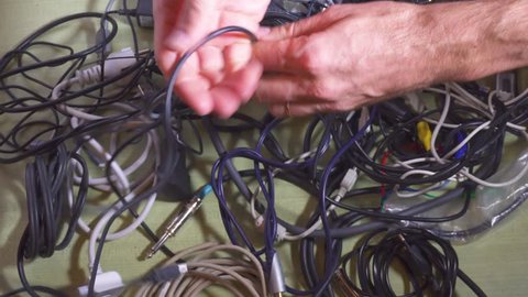 Man untangling tangled cables. Closeup.