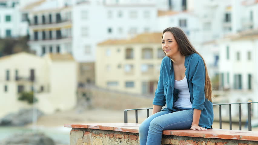 Happy woman looks away when her boyfriend arrives in a coast town on vacation