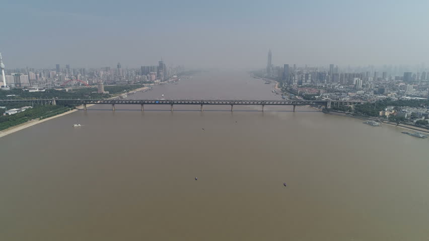 Wide angle panoramic drone shot of Wuhan skyline and historic bridge spanning the wide Yangtze river, urban development and infrastructure in China
