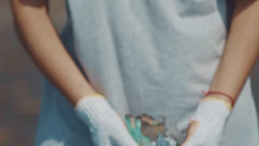 Closeup of hands of a volunteer showing plastic trash collected on the ocean beach. Volunteers cleaning the beach. Environmental awareness and volunteering, recycling concept. Royalty-Free Stock Footage #1021118404