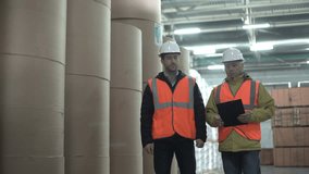 Workers walking and discussing stock inventory against tall shelves, in a warehouse with bright lamps. - Powered by Shutterstock - Get 15% off with code: PIKWIZARD15