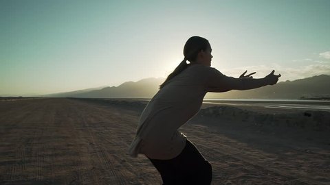 Adorable dancer girl dancing freestyle in the desert in sun rays slow motion