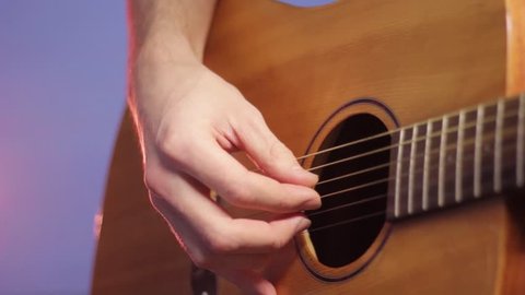 guitarist's right hand jerking the strings of an acoustic guitar close-up, fingerstyle playing